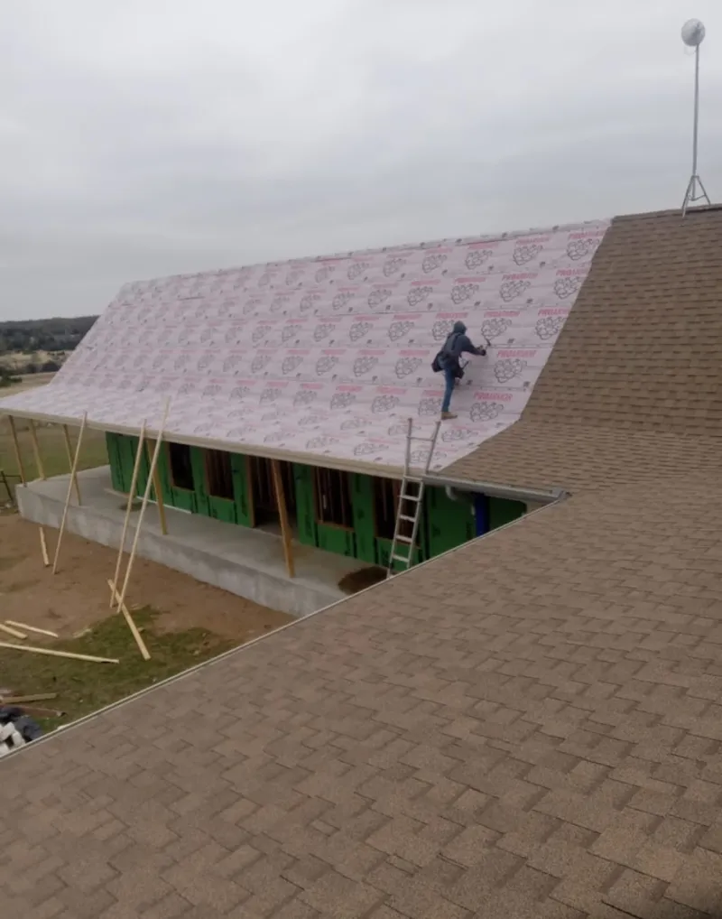 Worker preparing underlayment for a metal roof installation in Marshall